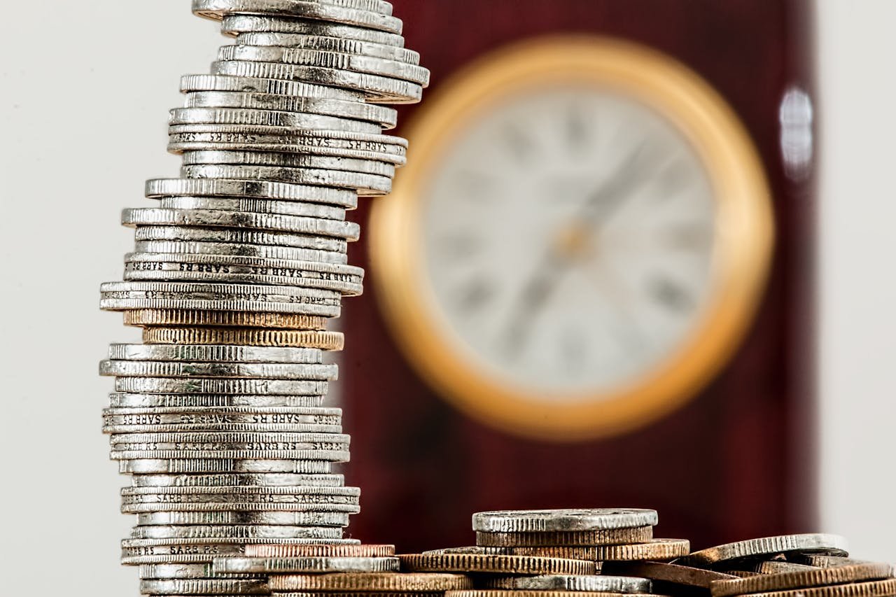 Services A close-up image of stacked coins with a blurred clock, symbolizing time and money relationship.